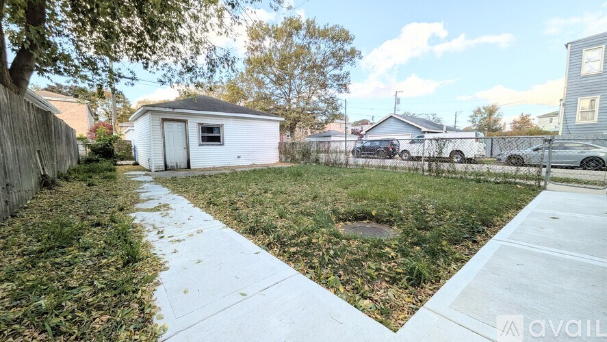 A backyard with a white fence and a small white building.