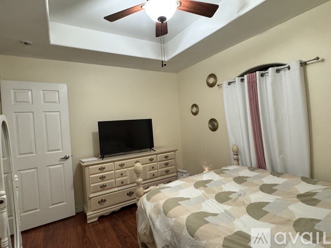 A bedroom with a bed, dresser, and television.