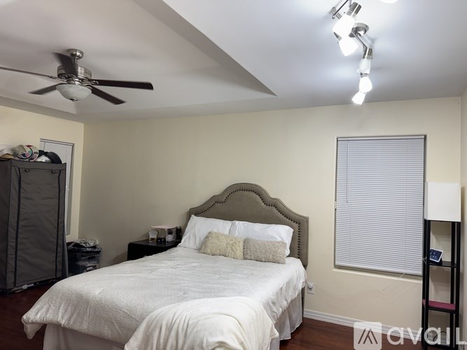 A bedroom with a bed, nightstand, and a ceiling fan.