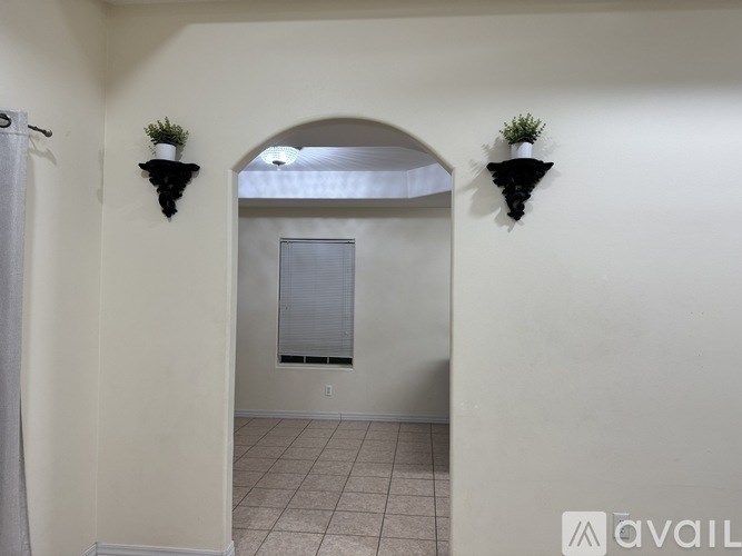 A hallway with two planters on the wall and a door at the end.