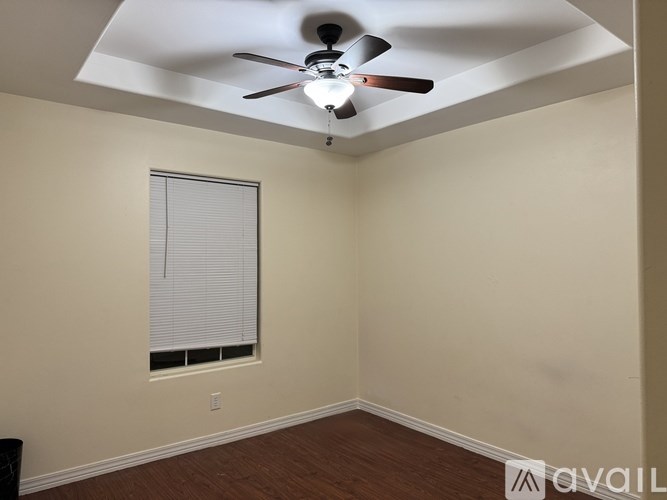 A room with a ceiling fan and a window with blinds.