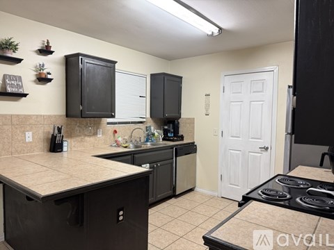 A kitchen with black cabinets and a white door.