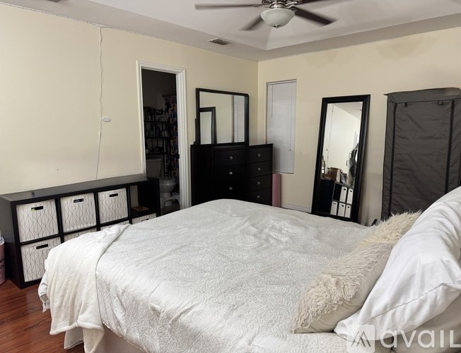 A bedroom with a large bed and a dresser with mirrors.