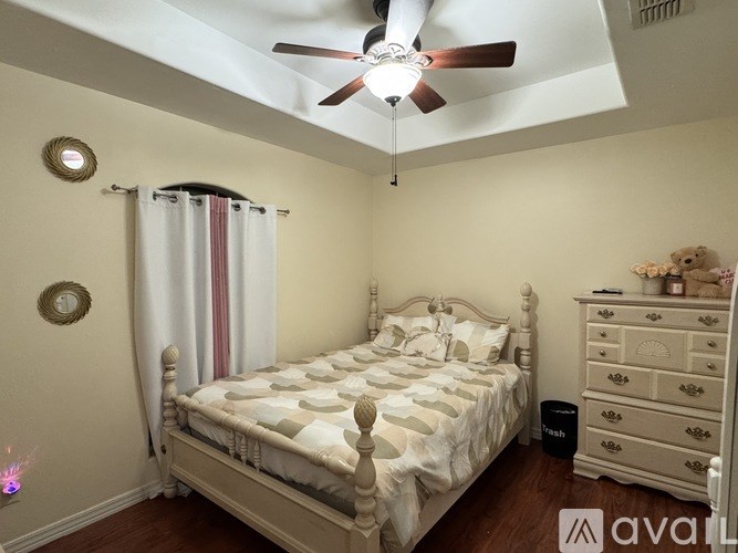 A bedroom with a bed, dresser, and ceiling fan.