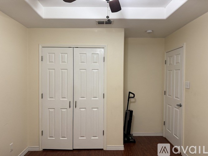 A room with a white door and a black vacuum cleaner.