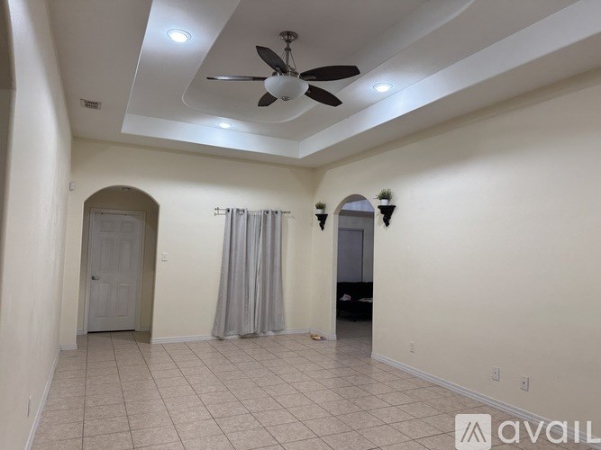 A spacious room with a ceiling fan and tiled flooring.