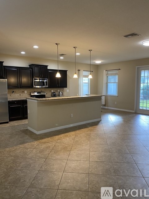 A kitchen with black cabinets and a beige island.