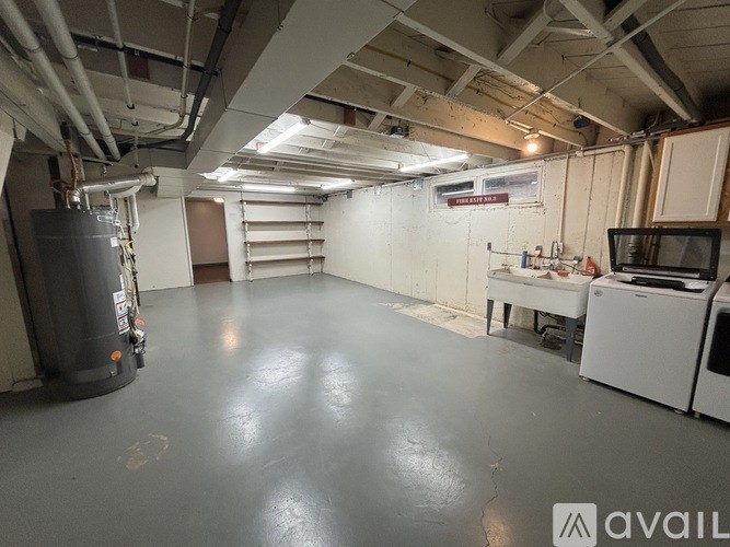 A large, empty room with a grey floor and white walls, equipped with a stove and a microwave.