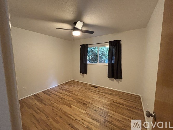 A room with wooden flooring and a ceiling fan.