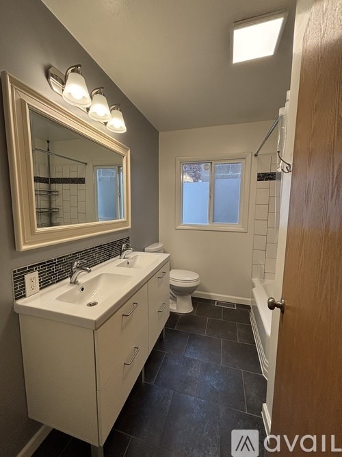 A bathroom with a sink, mirror, toilet and a door.