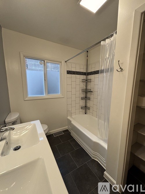 A bathroom with a white sink, black tiles, and a window.