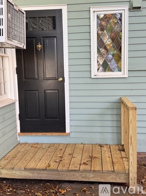 A black door with a wooden frame and a wooden porch.
