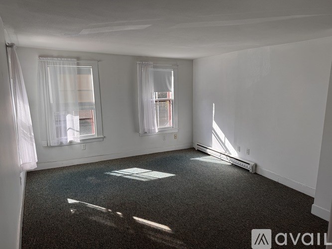 A room with a carpeted floor and two windows.