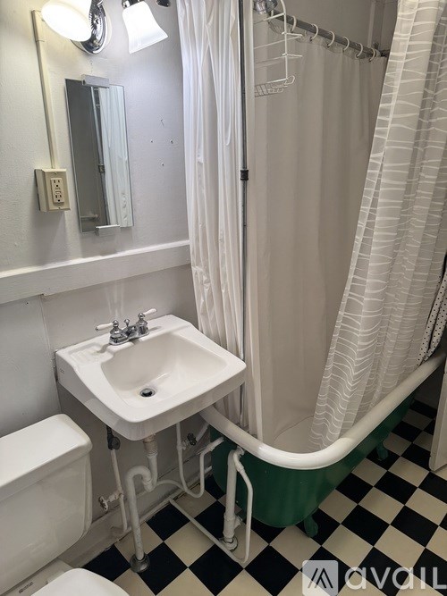 A white sink in a bathroom with a black and white checkered floor.