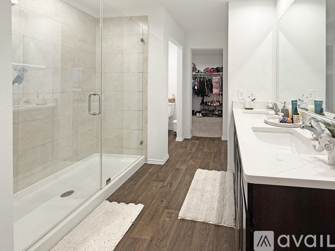 A bathroom with a white tub and sink, a white rug, and a walk-in shower.