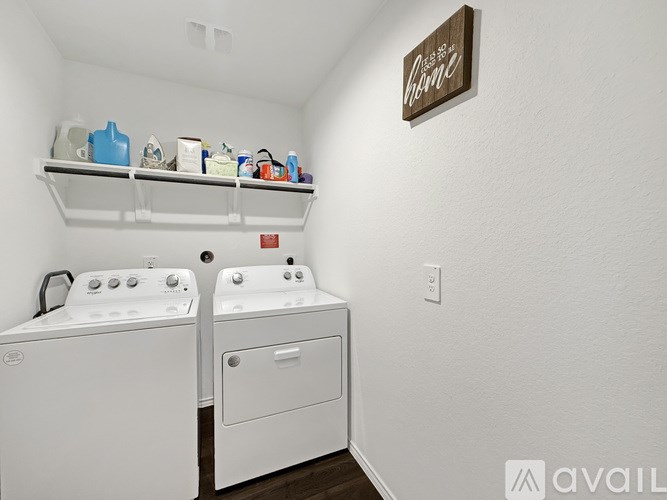 A laundry room with a washer and dryer and a shelf above them.