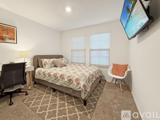 A bedroom with a bed, chair, and television.