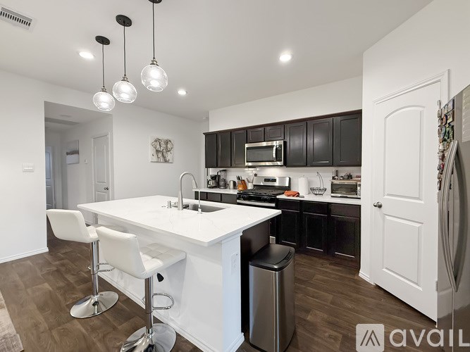 A modern kitchen with a white island and black cabinets.