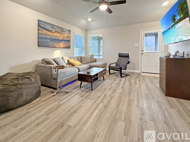 A living room with a grey couch, a chair, a coffee table, and a painting on the wall.