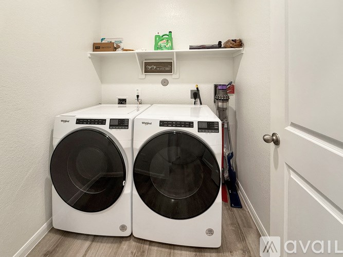 Two white front load washing machines in a small laundry room.