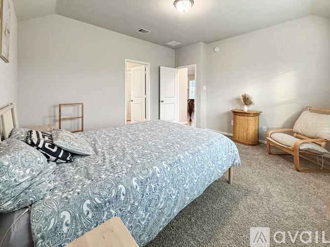 A bedroom with a bed, a chair, and a nightstand.