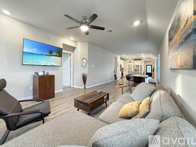 A living room with a grey couch and a television on the wall.