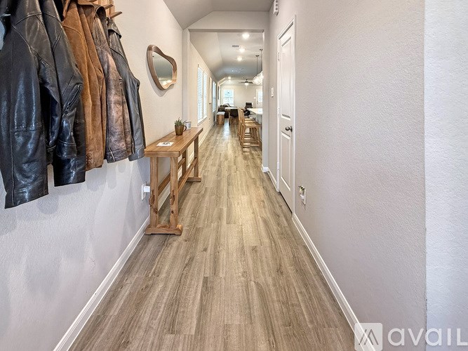 A hallway with a table and jackets hanging on the wall.