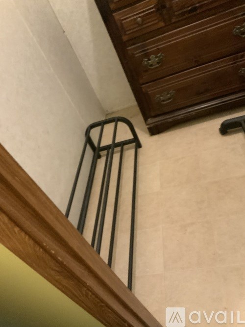 A black metal railing is attached to a wooden staircase.