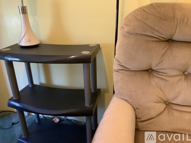 A person is sitting on a beige chair with a black table beside it.