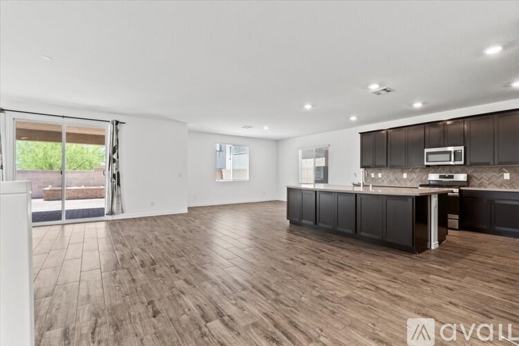 A spacious kitchen with dark brown cabinets and a wooden floor.