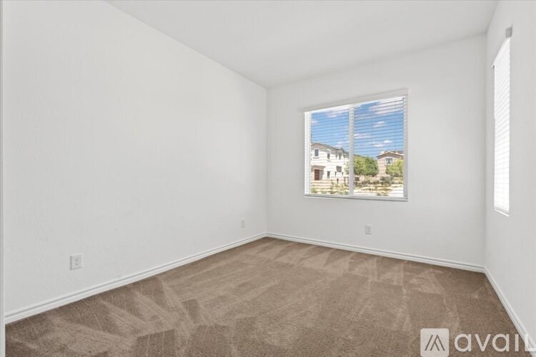 A room with a carpeted floor and a window showing a view of a house.