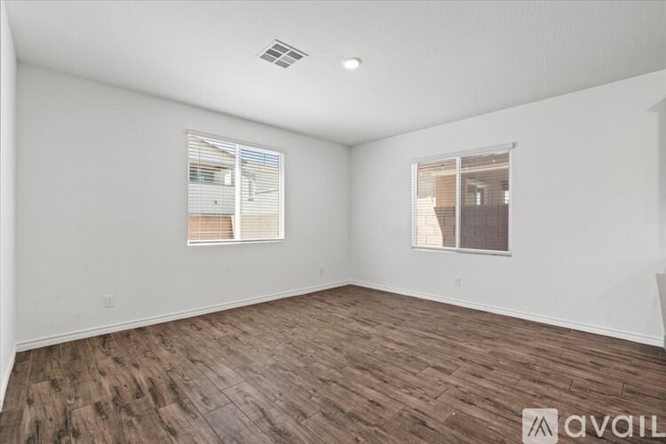 A room with wooden flooring and two windows.
