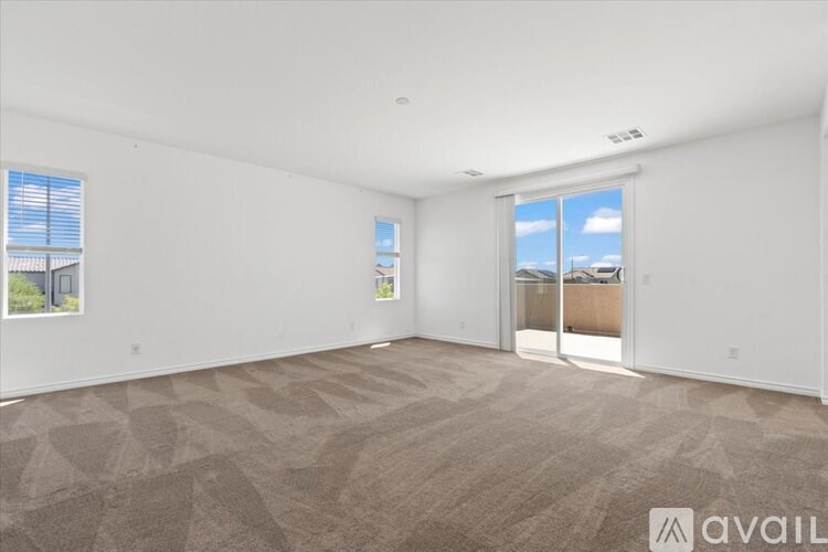 A room with a carpeted floor and a window with blinds.