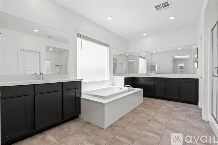 A large, modern bathroom with a white bathtub and black cabinetry.