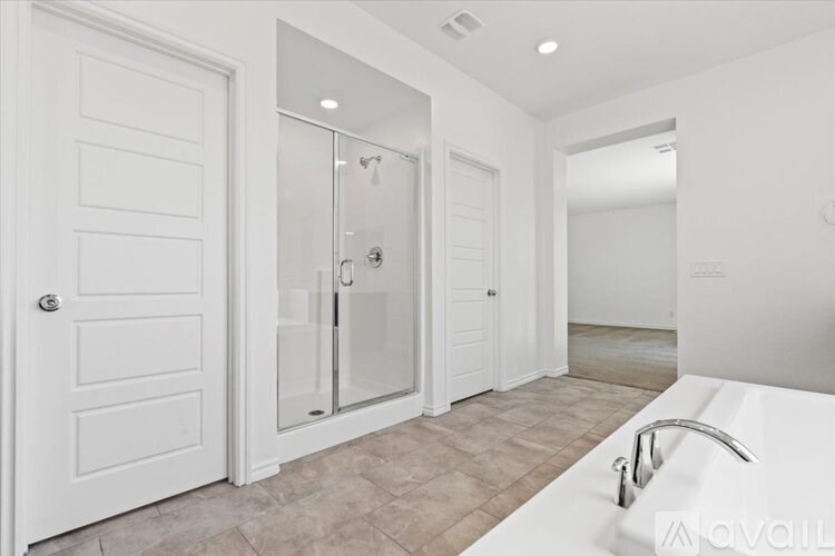 A white bathroom with a glass shower door and a white bathtub.