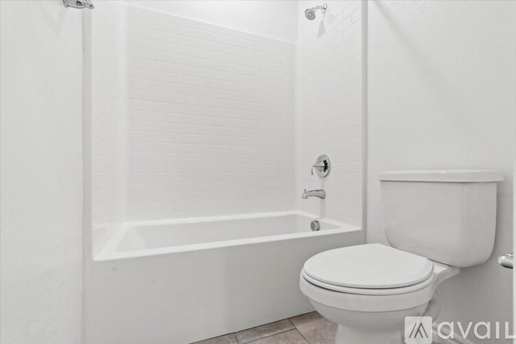 A white toilet sits next to a white bathtub in a bathroom.