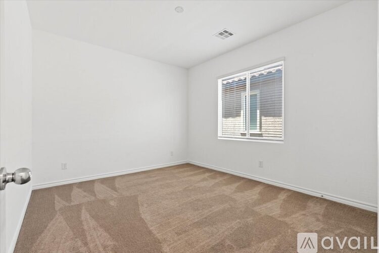A room with a carpeted floor and a window with blinds.