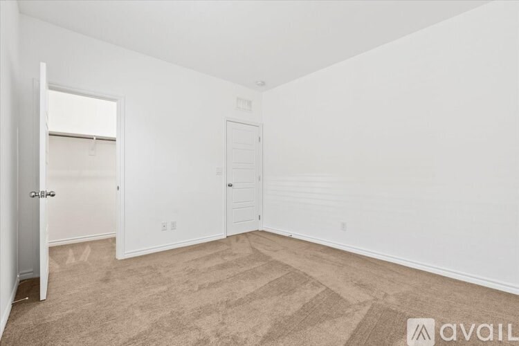 A room with a carpeted floor and two doors.