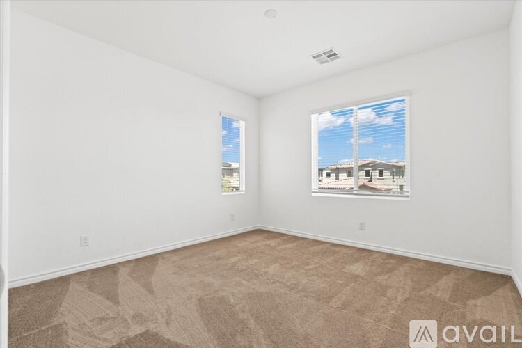 A room with a carpeted floor and a window showing a view of a house.