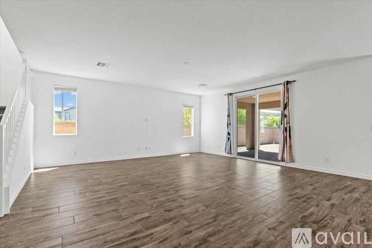 A spacious room with wooden flooring and a sliding glass door leading to a balcony.