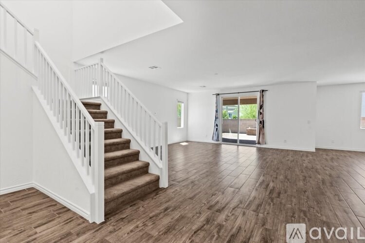 A spacious room with wooden flooring and a staircase leading to the upper level.