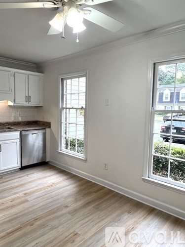 A kitchen with white cabinets and a wooden floor.