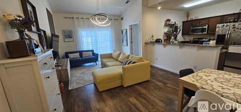 A living room with a yellow couch and a kitchen area with a microwave and oven.