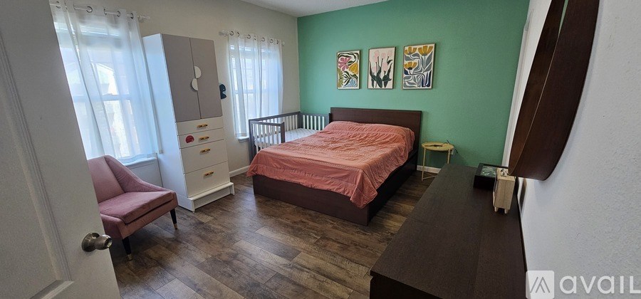 A bedroom with a pink bed and a chair.