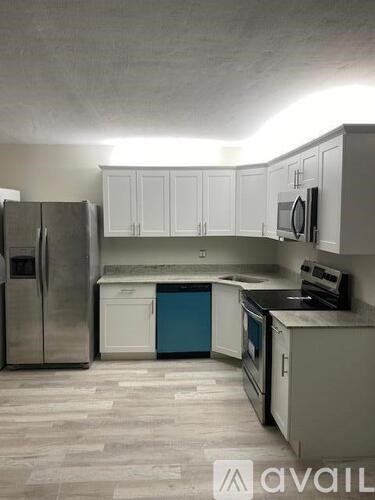 A kitchen with a refrigerator, microwave, oven, and cabinets.