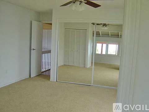 A bedroom with a mirrored closet door and a ceiling fan.