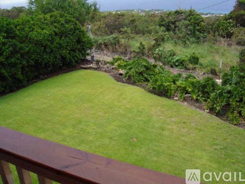 A backyard with a green lawn and a wooden deck.