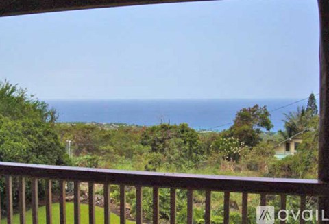A wooden balcony overlooks a lush green landscape.
