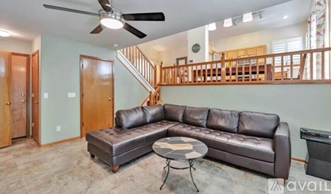 A living room with a brown leather couch and a ceiling fan.