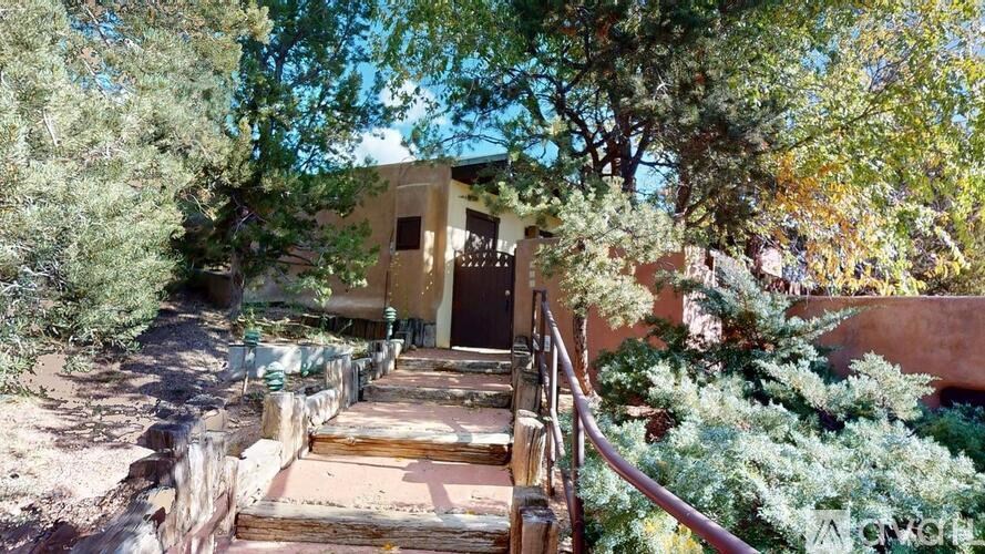 A house surrounded by trees and a wooden staircase leading to the front door.
